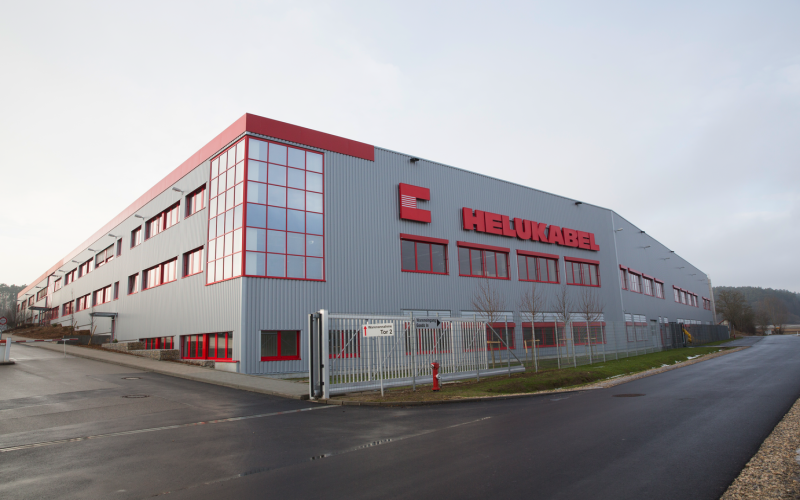 An outside photograph of HELUKABEL Windsbach in Germany where cables are both manufactured and tested using state-of-the-art facilities and equipment. 
						