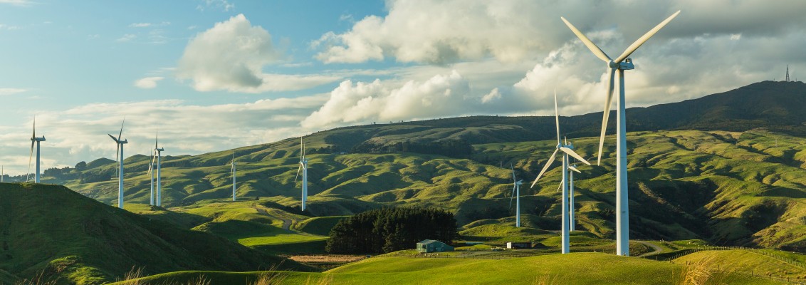 A photograph of the rolling English countryside hills adorned with clean, white, wind turbines.